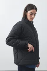 Campera acolchada de nylon color negro, con cuello alto, cierre frontal y botones a presión. Presenta un diseño de rombos y forro interior suave.