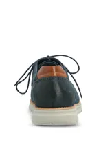 Zapato de estilo derby en color azul marino, confeccionado en cuero con detalles de perforaciones tipo brogue, talón en tono tostado y suela de goma gris claro.