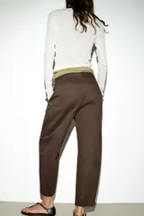 Pantalón de tiro medio con diseño barrel, pernera holgada que se estrecha hacia el tobillo, bolsillos delanteros y bolsillos de plastrón en la espalda. Confeccionado en tejido con textura de espiga, cuenta con cierre frontal de cremallera, botón interior y gancho.