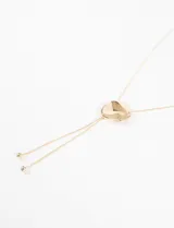 Collar dorado con dije irregular y cordones finos colgantes.