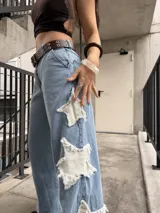Jeans rígido de corte wide leg, tiro medio y color celeste, con diseño de estrellas grandes desflecadas en los laterales de las piernas.