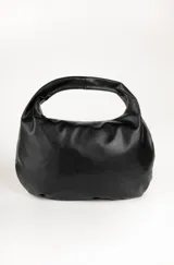 Bolso negro tipo hobo de cuero sintético, con asa corta fija y cierre superior.