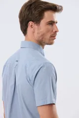Camisa de manga corta de algodón en color celeste con microdiseño geométrico a cuadros, cuello camisero y bolsillo frontal con logo bordado.
