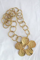 Collar de cadena dorada con eslabones circulares y dije de flor con textura.