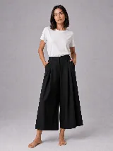 Pantalón de corte sastrero con silueta amplia y largo cropped por encima del tobillo. Presenta pinzas en la cintura, bolsillos laterales y cierre frontal con botón.
