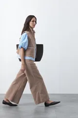 Pantalón de pana de corte wide leg, color marrón oscuro, con calce relajado y detalle de bordado en el borde de los bolsillos delanteros.