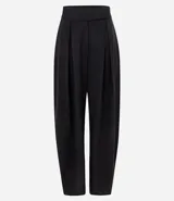 Pantalón de sastrería corte barrel, color marrón oscuro, con pliegues delanteros, cintura con cierre desplazado y piernas anchas.