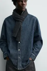 Camisa de corte relajado confeccionada en denim de algodón, con cuello solapa, manga larga con puños abotonados y cierre frontal de botones.