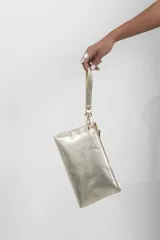 Sobre de fiesta tipo clutch color dorado metalizado, confeccionado 100% en cuero vacuno, con cierre superior y correa de muñeca desmontable.