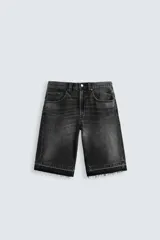 Bermuda de denim de algodón, color negro lavado, de corte ancho (baggy fit) y tiro medio. Presenta cinco bolsillos y bajo con acabado irregular deshilachado.