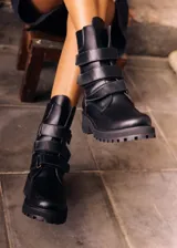 Botas altas de cuero marrón con suela track y tres tiras con hebillas metálicas en la caña.
