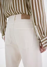 Jeans de algodón estilo wide leg en color beige, con diseño de tiro medio, cinco bolsillos, trabillas para cinturón y cierre frontal con botón y cremallera.