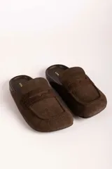 Zueco tipo mocasín destalonado en color verde oliva, con textura grabada efecto cocodrilo y acabado en gamuza.