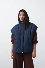 Chaleco acolchado de nylon con diseño capitoneado, cuello alto y cierre frontal con botones a presión. Presenta un calce amplio y versátil.