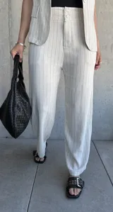 Pantalón de vestir color natural con finas rayas verticales negras, de corte holgado y tiro alto.