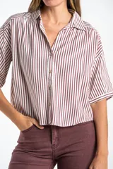 Camisa de corte oversize con estampado de rayas verticales, cuello clásico y mangas cortas. Presenta cierre frontal con botones y un diseño fluido y ligero.