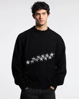 Sweater de punto negro con diseño de estrellas bordadas en color gris en el frente. Presenta cuello, puños y ruedo con terminaciones desflecadas y un corte holgado.