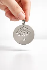 Dije circular de acero inoxidable con diseño calado de árbol de la vida.