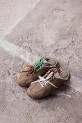 Zuecos de cuero color beige, con cordones marrones y verdes, y detalles de costuras.