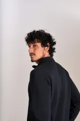 Buzo de cuello alto con cierre frontal parcial, manga larga y puños acanalados. Presenta un diseño liso en color negro con el logo de la marca bordado en el pecho.