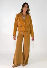 Chaqueta de pana color marrón, con solapas desflecadas, cierre frontal con botones y bolsillos delanteros con solapa desflecada.