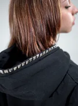 Buzo canguro negro con capucha, corte regular fit, de manga larga, con gran diseño de cruz frontal elaborado con tachas metálicas plateadas y tachas en el borde de la capucha.