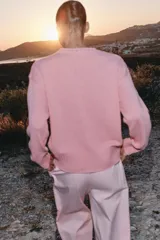 Sweater de punto color rosado con cuello redondo y manga larga, de bajo asimétrico con acabados en rib.