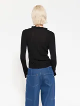 Top color beige de tejido de punto acanalado, con cuello redondo y mangas largas con volados en los puños.