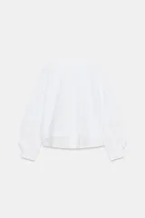 Camiseta de corte oversize confeccionada en algodón, con cuello redondo y mangas largas terminadas en puños con botones. Presenta un diseño de tejidos combinados a tono y bajo asimétrico.