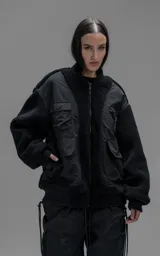 Campera estilo bomber unisex, confeccionada en una combinación de corderito sintético y paneles de ripstop. Presenta un diseño utilitario con múltiples bolsillos frontales con cierres y broches a presión, cuello, puños y ruedo en ribb elástico.