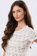 Remera de manga corta con cuello redondo, confeccionada en algodón con estampa de diseño floral en tonos rosados y verdes sobre base beige.