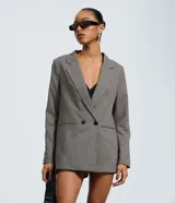Blazer sastre de corte regular con estampado de cuadros, solapas clásicas y cierre frontal con dos botones. Presenta bolsillos embutidos y un diseño estructurado.