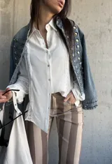 Camisa blanca de manga larga con detalles de encaje y calados verticales en el frente y las mangas.