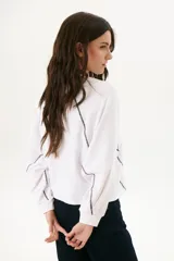 Buzo negro de corte cropped con mangas largas abullonadas y costuras a la vista en color blanco.