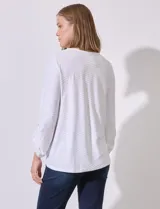 Blusa blanca de poliéster y elastano con textura en relieve, cuello redondo, manga 3/4 con ajuste en el puño y ruedo con nudo.