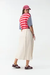 Falda midi de lino color beige, de tiro alto y corte recto, con abertura delantera y cierre cruzado sutil.