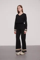 Pantalón negro de tejido de punto con corte palazzo y cintura alta. Presenta dos franjas horizontales color crema en el ruedo.