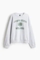 Buzo de cuello redondo con hombros caídos y diseño estampado en el frente. Presenta puños y bajo acanalados, con interior cepillado suave.