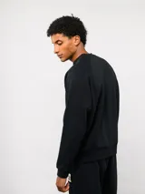 Buzo de felpa color crema, con cuello redondo, manga larga tipo raglán y puños y dobladillo acanalados. Incluye una etiqueta con el logo de Umbro en la parte delantera.