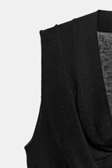 Top cruzado de punto fino color negro, con escote fluido y diseño sin mangas.