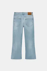 Jeans de tiro medio y corte bootcut cropped de Zara Woman Collection. Confeccionados en denim de efecto lavado en color celeste, presentan diseño de cinco bolsillos, trabillas para cinto, detalle de rotura en la rodilla izquierda y bajo evasé sin costuras. Cierre frontal con cremallera y botón metálico.