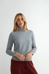 Polera de cuello alto y manga larga, confeccionada en tejido de punto fino de color gris.