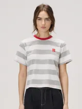 Remera de corte clásico con diseño de rayas horizontales grises y blancas, cuello redondo rojo y pequeño logo bordado en el pecho.