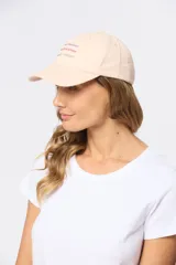 Gorro con visera de lona rosado con bordado frontal en tonos verde y violeta.