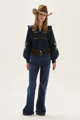 Blusa azul marino de algodón con volados en los hombros, mangas largas abullonadas y detalles de bordados florales y geométricos en el pecho y las mangas.