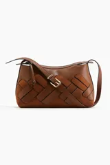 Cartera de hombro color marrón, con diseño trenzado oversized que combina secciones de cuero liso y gamuza. Cuenta con cierre superior, forro interior y correa ajustable con hebilla metálica.