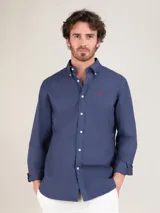 Camisa azul de hombre confeccionada en 100% algodón, tintada en prenda envejecida para darle un acabado vintage. Corte Regular Fit, cuello buttondown y cierre con botones. Manga larga terminada en puño simple y logo en el pecho bordado.