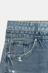 Jeans de tiro medio con cinco bolsillos, cintura doble a contraste y detalles de rotos. Cierre frontal con cremallera y botones metálicos.