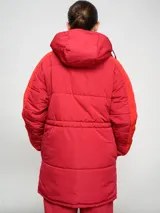 Parka larga de abrigo Umbro del Club Nacional de Football, color rojo con detalles en naranja en las mangas. Cuenta con capucha, cierre frontal con botones a presión y escudo del club bordado en el pecho.