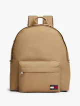 Mochila de diseño redondeado color beige, con compartimento principal y bolsillo frontal con cierre. Incluye parche con logo de la marca en la parte inferior, asa superior y correas acolchadas ajustables.